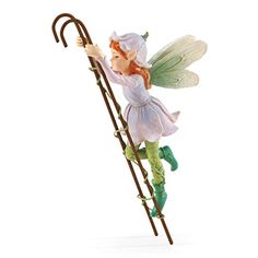 a figurine of a fairy holding a stick and wearing green shoes, standing next to a white background