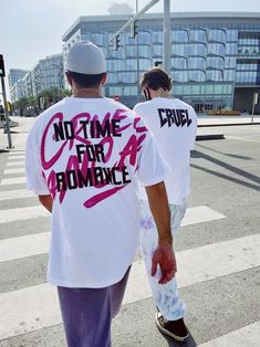 two men walking across a cross walk wearing t - shirts that say no time for romance