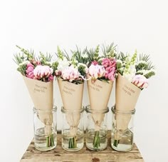 four vases filled with flowers sitting on top of a wooden table