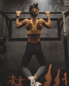 a woman is doing squats on a bar in the middle of a crossfit gym