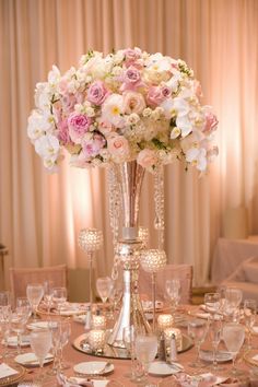 a tall vase filled with pink and white flowers on top of a dining room table