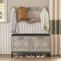 a coat rack with shoes on it next to a bench and curtains in a room