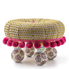 an ottoman with pom poms on the bottom and two small balls in front