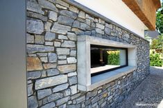 a stone building with an open window on the outside wall and graveled ground around it