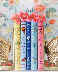 the books are lined up next to each other with pink flowers in front of them