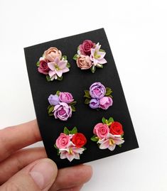 a hand holding a piece of paper that has flowers on it and is next to a black card