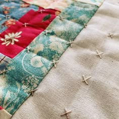 a close up view of a patchwork quilt that has been stitched together with pins