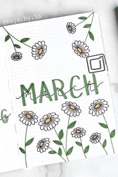 an open notebook with flowers and the word march written in cursive writing on it