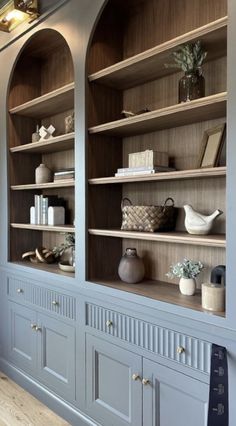 an empty bookcase with many books and vases on it's shelves in a living room