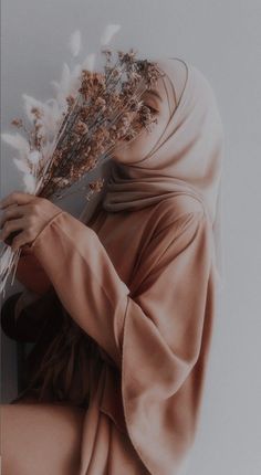 a woman wearing a headscarf and holding flowers