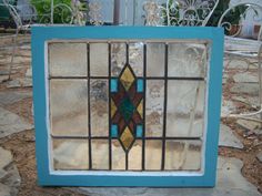 an old stained glass window sitting on top of a stone patio area with chairs in the background