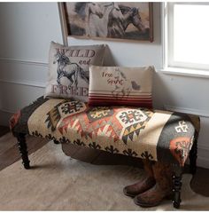 a bench that has some pillows on it and two pictures above the bench with horses