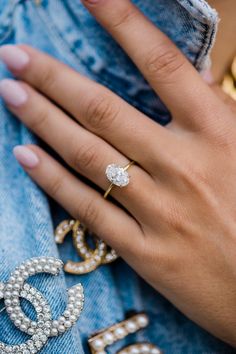 a close up of a person's hand wearing an engagement ring