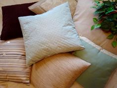 four pillows stacked on top of each other in front of a potted green plant