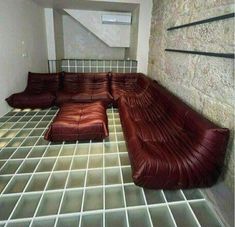 a couch sitting on top of a tiled floor next to a stair case in an empty room