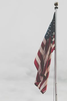 an american flag flying in the wind on a cloudy day with no one around it