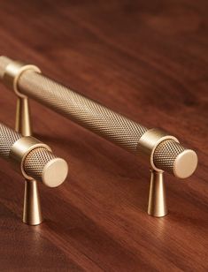 two gold colored microphones sitting on top of a wooden table