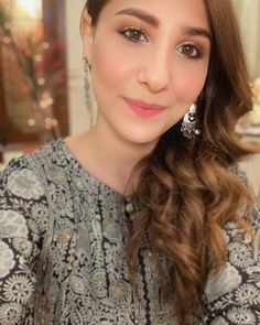 a close up of a person with long hair wearing earrings and a dress in front of a table