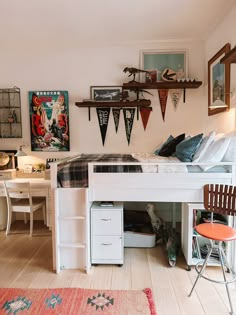 a loft bed with desk underneath it in a room filled with pictures and other items