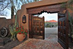 the entrance to an adobe style home with cactus and cacti