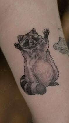 a small raccoon tattoo on the arm