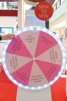 a pink and white spinning wheel on display in a building with the words spin to win above it