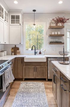 a kitchen with wooden cabinets and white counter tops, an area rug in front of the sink