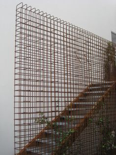 a metal fence with some plants growing out of it and stairs going up the side