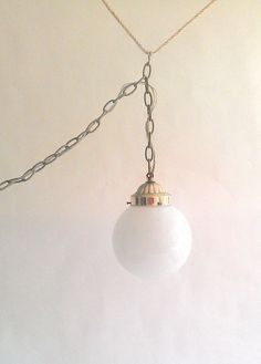 a white ball hanging from a chain on a wall with a light attached to it