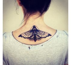 a woman's back neck with a butterfly tattoo on the upper part of her neck