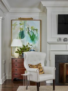 a living room with white furniture and a painting on the wall above a fire place