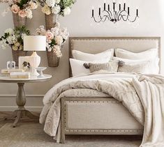 a bedroom with flowers and chandelier on the wall above the bed, along with two tables