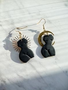 pair of earrings with sun and moon design on white marble surface, closeup view