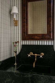 a bathroom sink sitting under a mirror next to a wall mounted faucet with a lamp on it