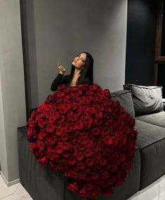 a woman sitting on top of a couch covered in red roses with her fingers up