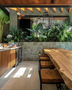 an outdoor dining area with wooden tables and hanging birdcages on the ceiling, surrounded by greenery