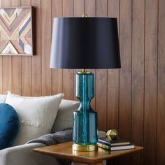 a blue lamp sitting on top of a wooden table next to a white couch in a living room