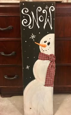 a snowman painted on the side of a wooden sign in a room with drawers