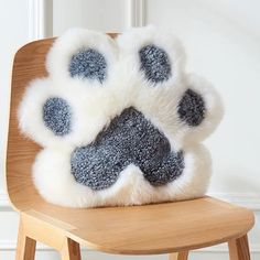 a white and gray dog paw pillow sitting on top of a wooden chair