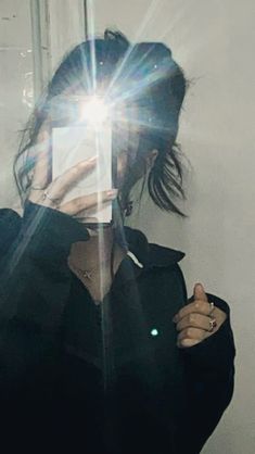 a woman taking a selfie in front of a mirror with the sun shining behind her