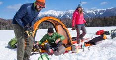 three people standing around a tent in the snow