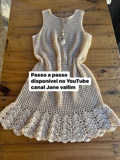 a crocheted white dress on top of a wooden table with the words, paso a passo disponivel no youtubee cantal jane vailim