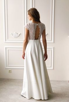 the back of a woman's white wedding dress with lace on top and sleeves