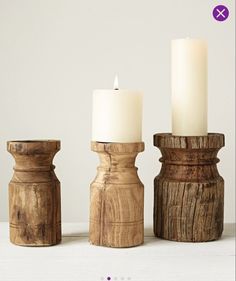 three wooden candlesticks sitting on top of a white table next to each other