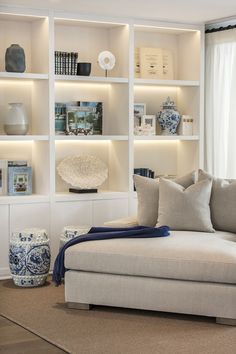 a living room filled with lots of furniture and bookshelves on top of white shelves