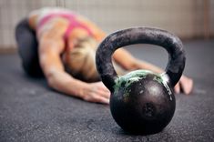 a woman laying on the floor with a kettle in front of her, while she is doing push ups