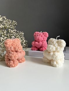 three crocheted teddy bears sitting next to each other on a white table with baby's breath flowers