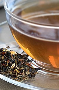 a glass bowl filled with tea next to a spoon