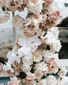 a bunch of white and pink flowers hanging from a metal pole in front of a window