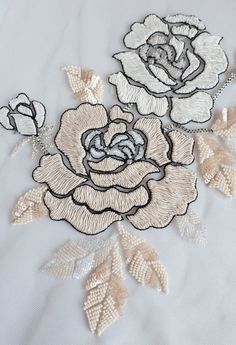 an embroidered rose with leaves on white fabric